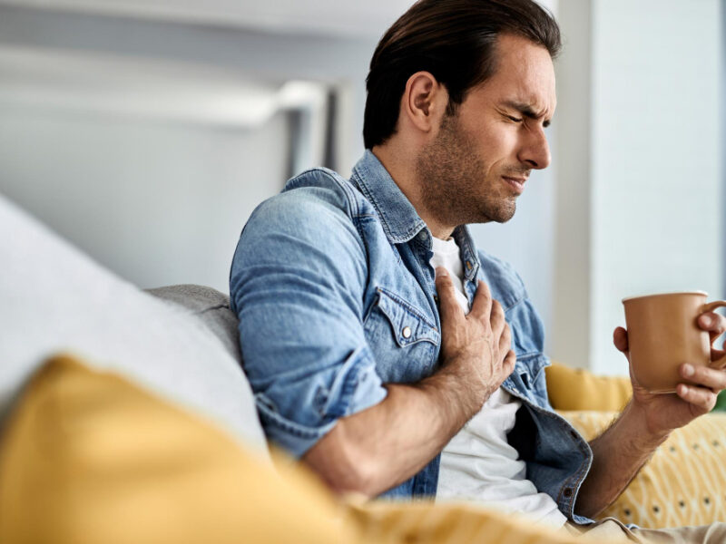 Young man with acid reflux and holding his chest in pain